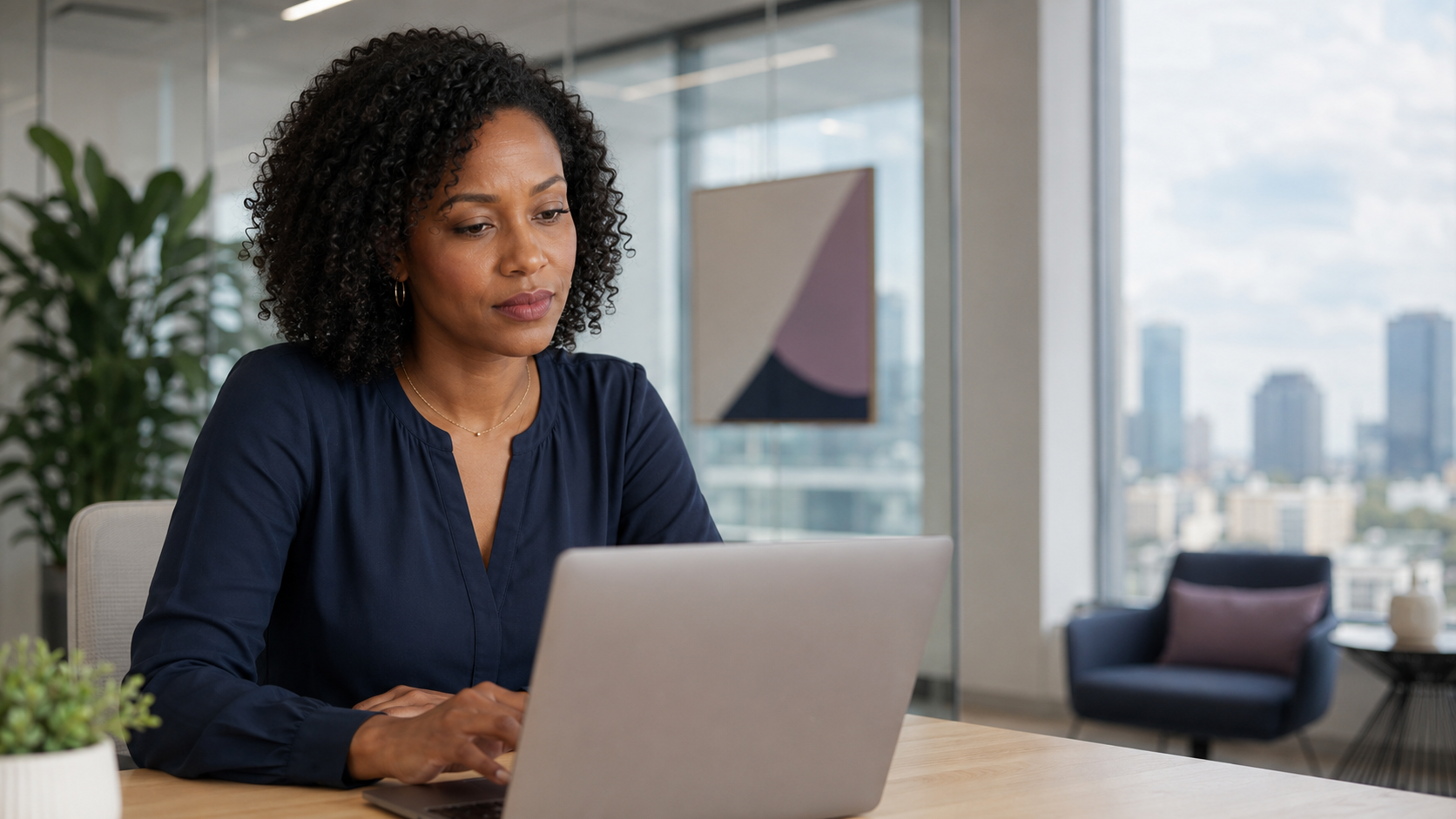 A professional pausing at her laptop in a bright modern office in mid-afternoon daylight, hand near the trackpad, caught in the moment before she sends a document and puts her name to it.